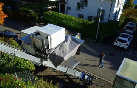 Möbelaufzug transportiert ein verpacktes Möbelstück von einem Haus in einen Umzugswagen