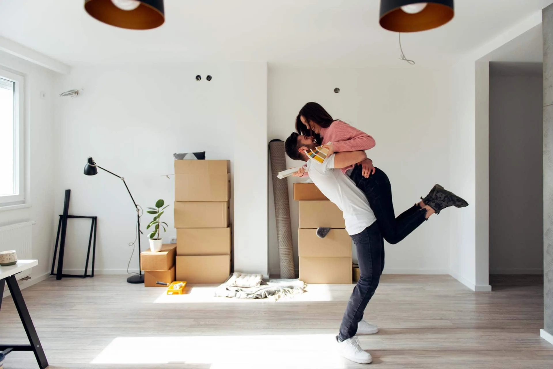 Junges Paar feiert den Umzug in eine neue Wohnung mit Kartons im Hintergrund