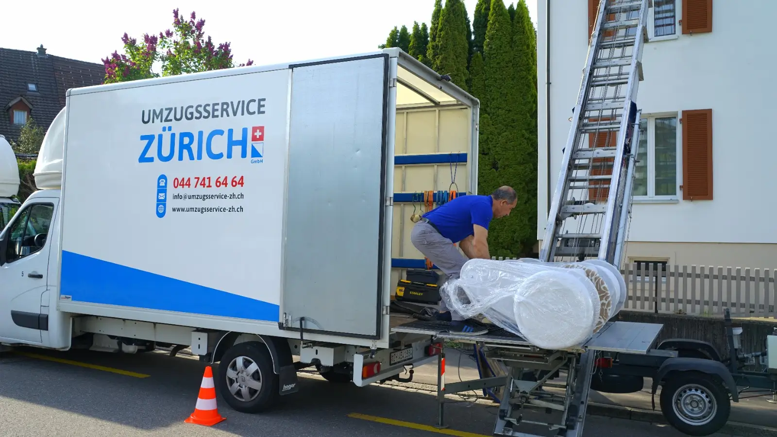 Möbelaufzug der Umzugsservice Zürich GmbH beim Transport eines verpackten Möbelstücks in den Umzugswagen