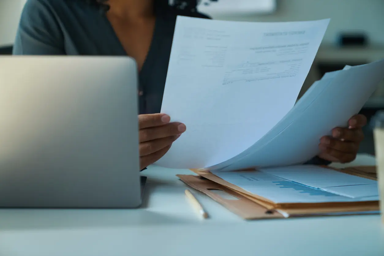 iStock-1417915464 Frau bearbeitet Wohnungskündigung-Vorlagen an einem Schreibtisch mit Laptop und Dokumenten in einem Büro.
