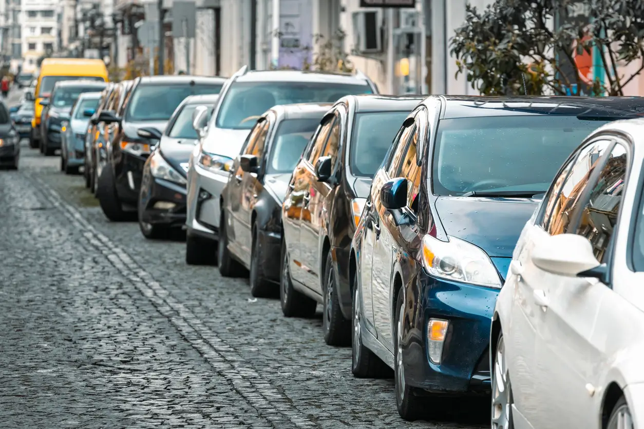 Eine Reihe geparkter Autos säumt eine gepflasterte Stadtstraße in der Schweiz.